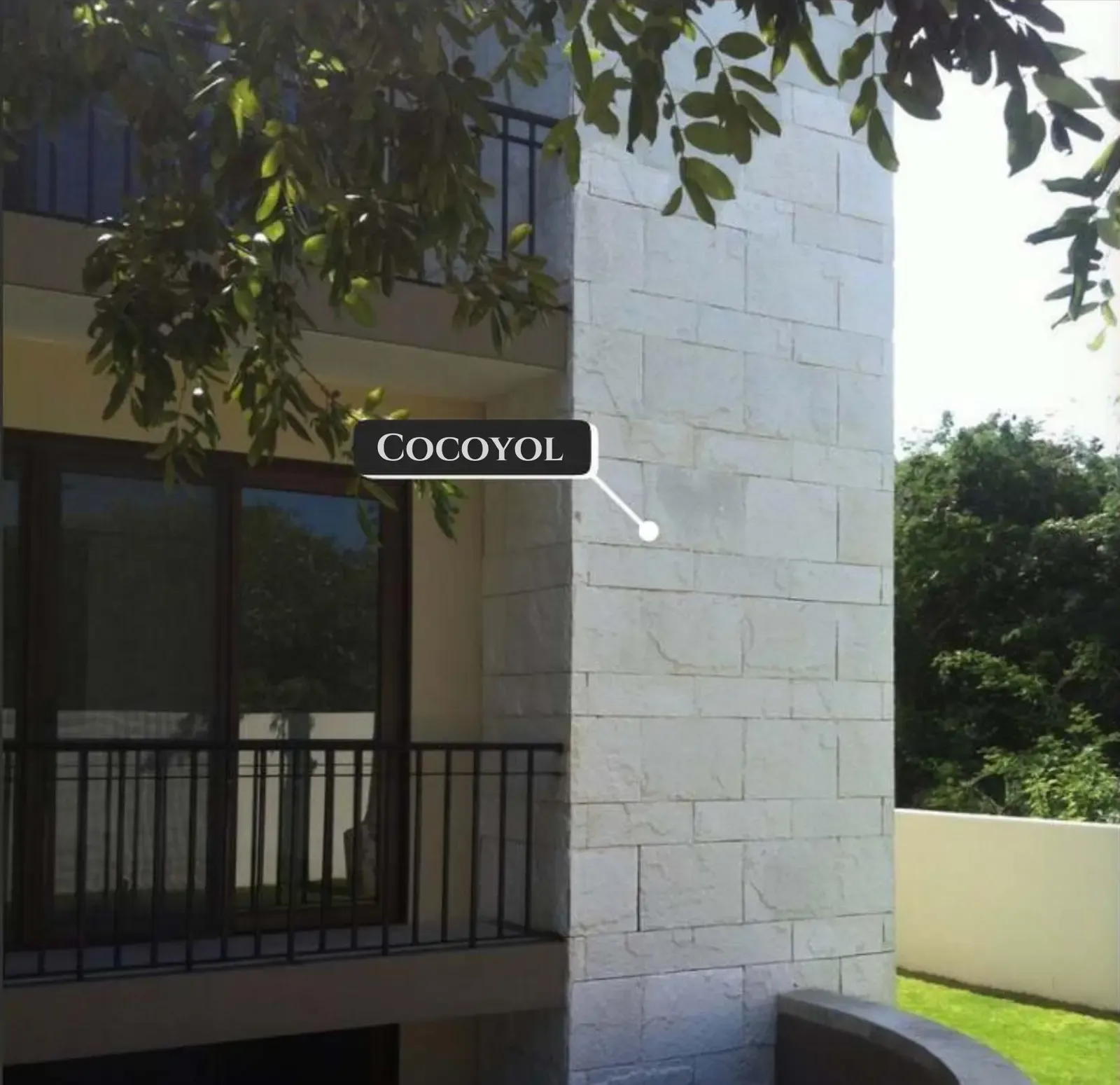 Rustic stone cladding on a curved exterior wall beside tropical planting